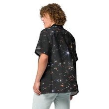 Load image into Gallery viewer, Digital mock up of a light-skinned person with curly broan hair wearing a short-sleeve button shirt printed with the JWST SMACS 0723 galaxy cluster image, shown from the side/rear