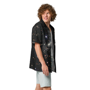 Digital mock up of a light-skinned person with curly broan hair wearing a short-sleeve button shirt printed with the JWST SMACS 0723 galaxy cluster image, shown from the side shirt unbuttoned