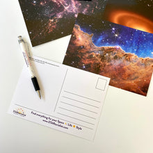 Load image into Gallery viewer, JWST First Year postcards arranged on a white surface, with one showing the back, and a STARtorialist pen