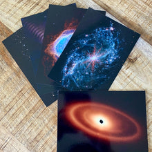 Load image into Gallery viewer, JWST First Year postcards arranged on a brown wood surface