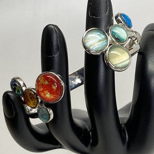 Mannequin hand  holding Solar System Cluster Adjustable Cuff Bracelet, with Sun and inner planets on left side of gap and giant planets and Pluto on right side of gap.