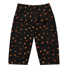 Load image into Gallery viewer, Digital mock-up of front of fitted shorts laid flat, black with small red and orange images of planet-forming disks at various angles.