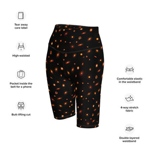 Digital mock-up of fitted shorts, black with small red and orange images of planet-forming disks at various angles, text: tear away label, high-waisted, pocket inside the belt for phone, butt-lifting cut, comfortable elastic in the waistband, 4-way stretch fabric, double-layered waistband.