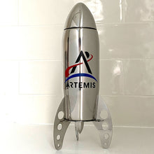 Load image into Gallery viewer, Stainless stell rocket-shaped cocktail shaker with the Artemis logo on a white tile background