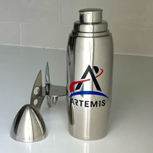 Load image into Gallery viewer, Stainless stell rocket-shaped cocktail shaker (disassembled) with the Artemis logo on a white tile background