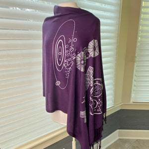 Psyche & Lucy Asteroid Missions Scarf (purple with silver asteroid and spaceraft illustrations) draped on a mannequin with a background of shaded windows.