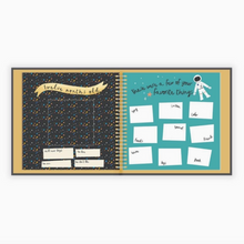 Load image into Gallery viewer, Baby memory book open showing two pages with space and astronaut details, shown on a white background
