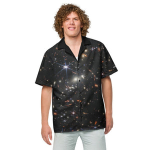 Digital mock up of a light-skinned person with curly brown hair wearing a short-sleeve button shirt printed with the JWST SMACS 0723 galaxy cluster image with black collar and buttons, shown from the front