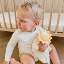 Load image into Gallery viewer, Baby sitting on the floor holding a plush toy with a sun design, in front of a wooden crib.