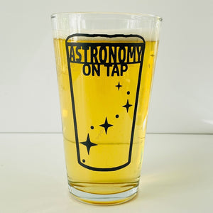 Astronomy on Tao logo pint glass filled with light yellow beer on a white nackground
