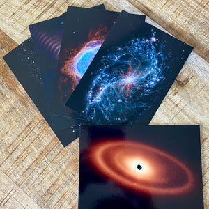 JWST First Year postcards arranged on a brown wood surface