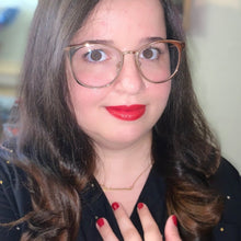 Load image into Gallery viewer, Katherine wearing the gold Astronomer nameplate necklace with a black gold-star-print shirt, red lipstick and nail polish