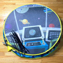 Load image into Gallery viewer, Rocketship play tent shown folded into a small circle with collapsable poles folded on top.