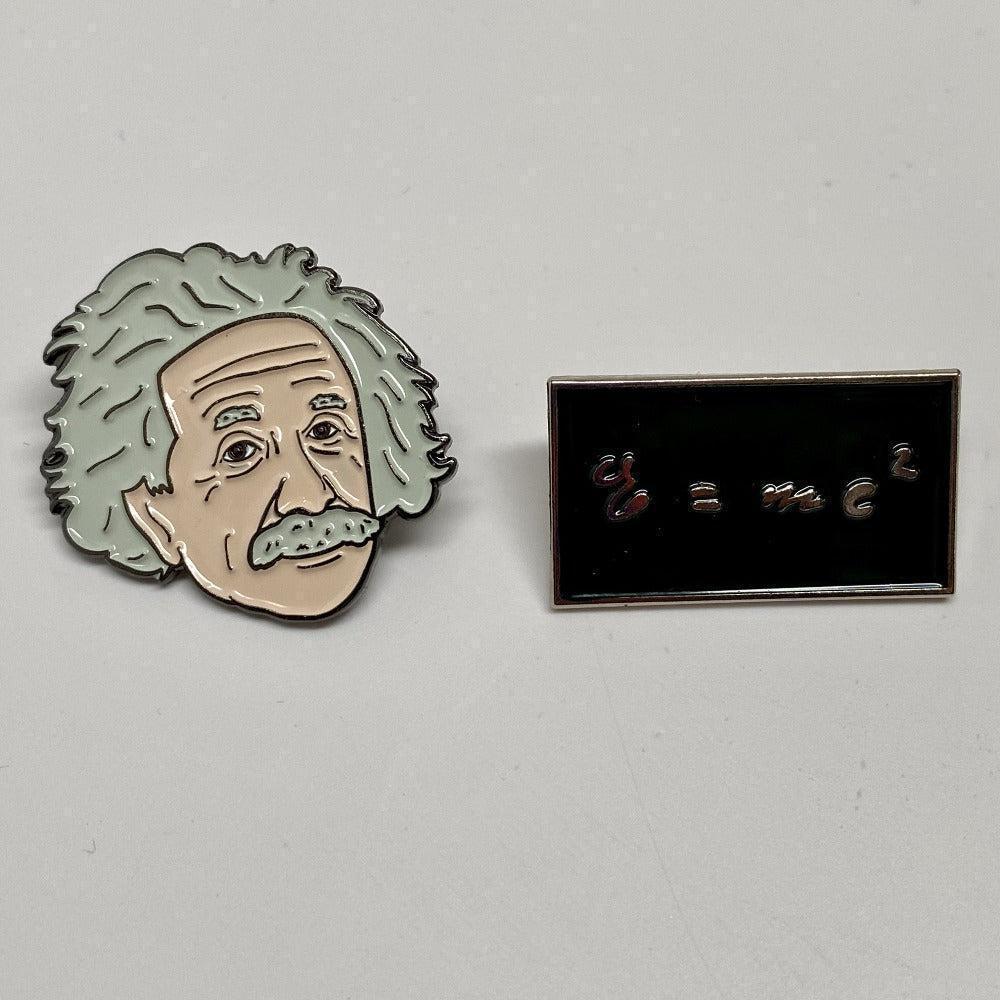 Pin with shape and image of Albert Einstein face, and rectangular black pin with equation E = mc^2 in metallic script.