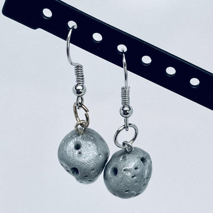 Asteroid Dangle Clay Earrings shown hanging from the diagtonal black bar of an earring display