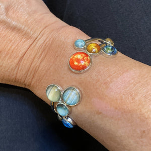 Adjustable Bracelet fitted on a wrist with giant planets and Pluto left of gap, and Sun and inner planets right of gap.