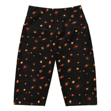 Load image into Gallery viewer, Digital mock-up of front of fitted shorts laid flat, black with small red and orange images of planet-forming disks at various angles. 