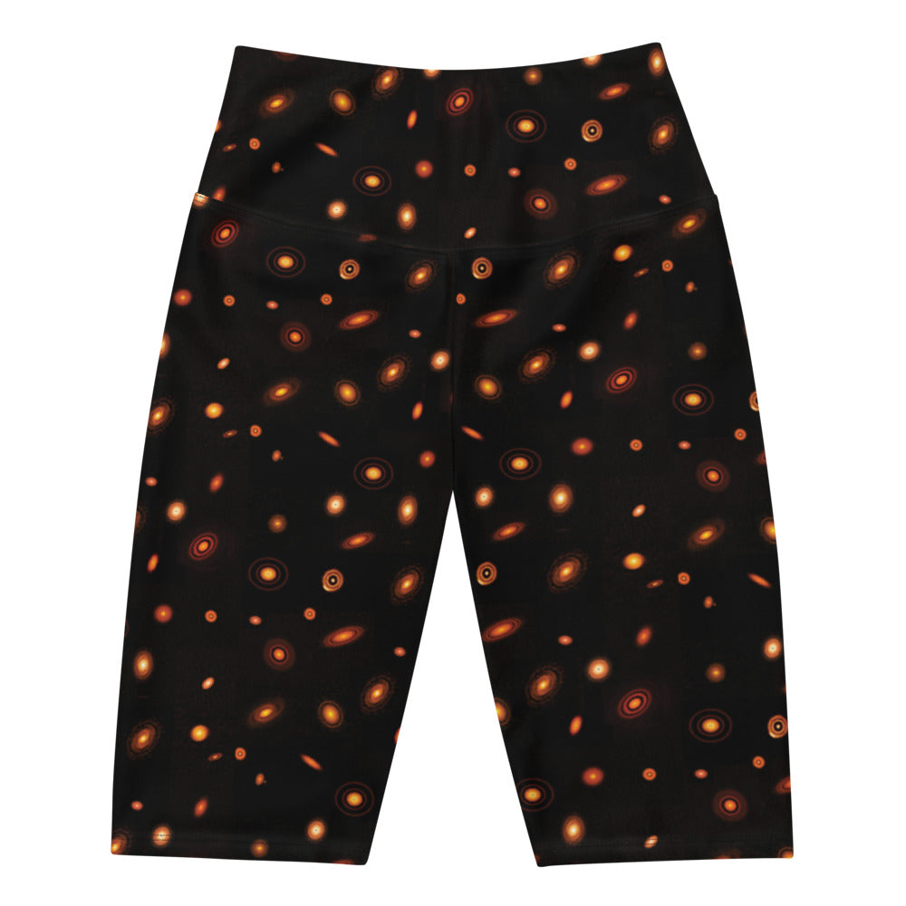 Digital mock-up of front of fitted shorts laid flat, black with small red and orange images of planet-forming disks at various angles. 
