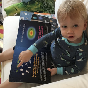 Child reading ABCs of Space, on page G is for Galaxies with galactic types and descriptions, and H is for Habitable zone showing the region around star.