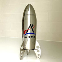 Load image into Gallery viewer, Stainless stell rocket-shaped cocktail shaker with the Artemis logo on a white tile background